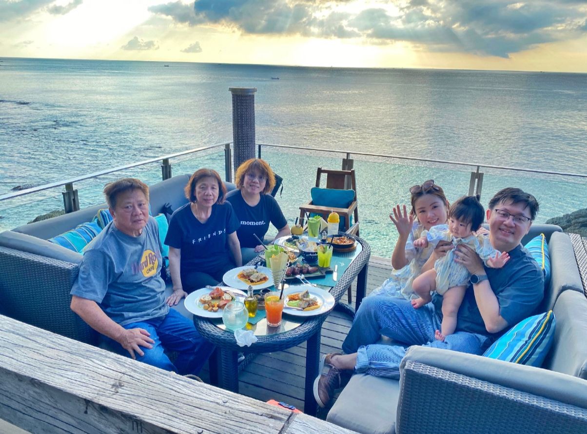 Family with toddler enjoying sunset dinner at a cliffside ocean restaurant in Bali