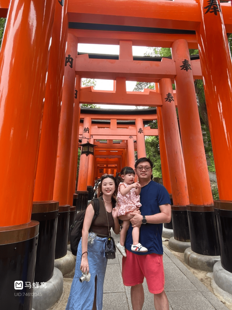 Family walking through the vermilion torii gates at Fushimi Inari Shrine in Kyoto, Japan, with a toddler in the foreground