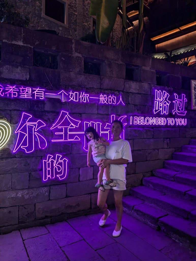 Grandma holding child under neon lights in Shibati Chongqing
