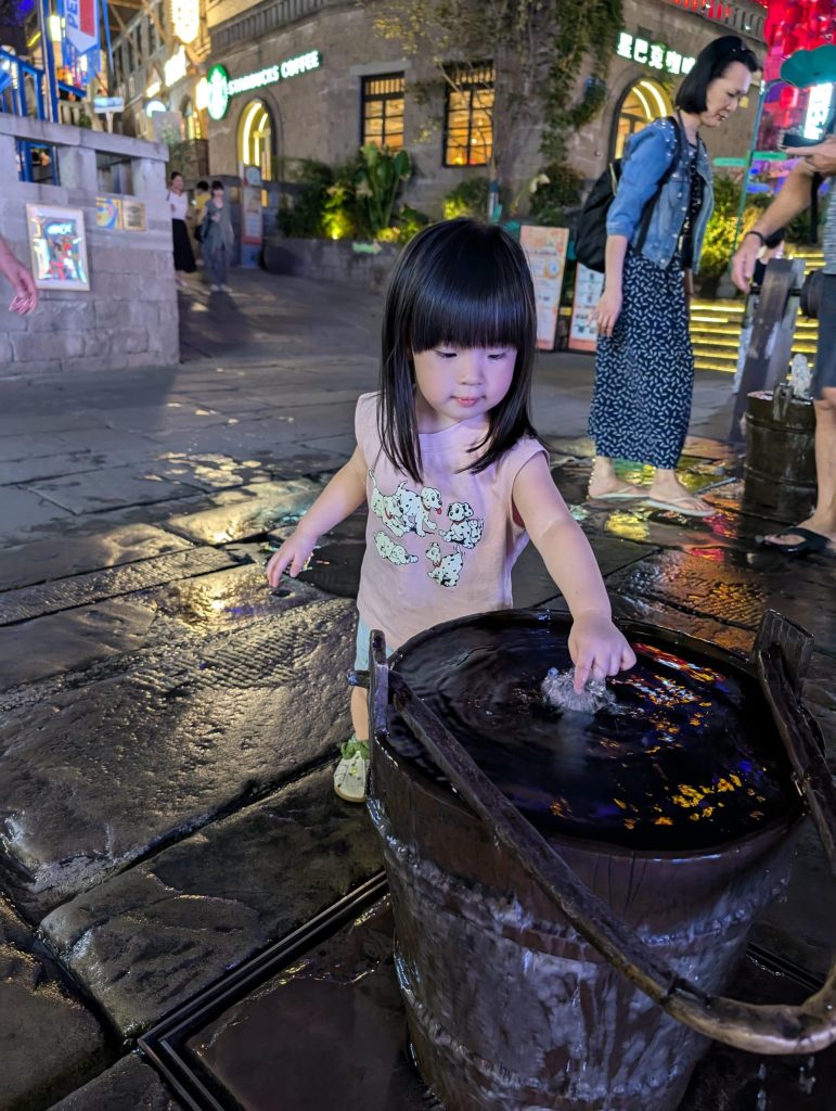 Young girl playing in traditional water fountain in Shibati, Chongqing.