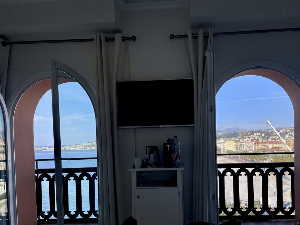 Hotel Suisse Nice Review: Iconic Sea Views on the French Riviera 9 Double arched balcony windows in Hôtel Suisse Nice room overlooking the bay and city skyline.