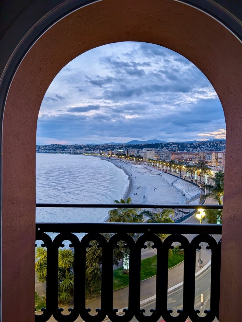 Hotel Suisse Nice Review: Iconic Sea Views on the French Riviera 8 Night view of illuminated Promenade des Anglais and Bay of Angels from Hôtel Suisse Nice balcony.