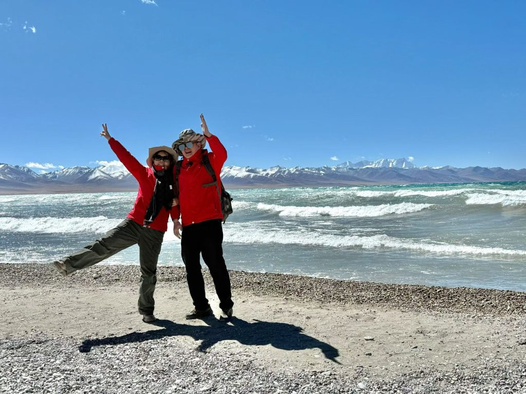 Namtso Lake Travel Guide: Lake in the Sky 9 Two travelers standing on the vast plain near Namtso with snow mountains in the background
