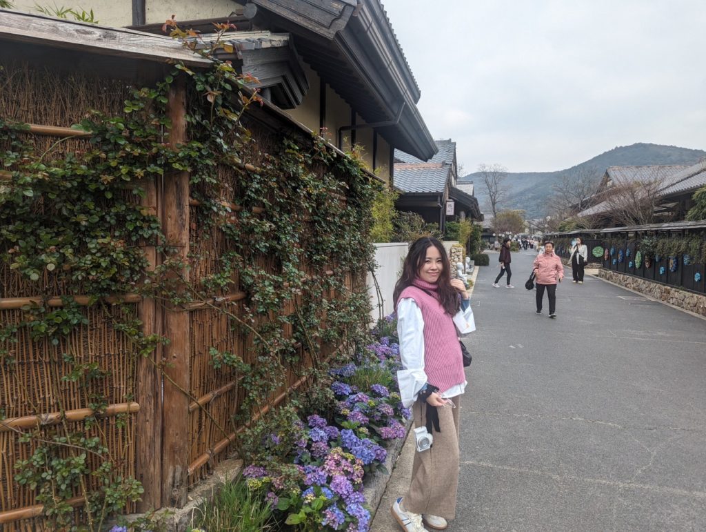 Wuxi Nianhua Bay: A Peaceful Zen Town Blending Tang-Song Architecture and Jiangnan Charm 10 Traveler walking along Tang-Song inspired streets lined with flowers.