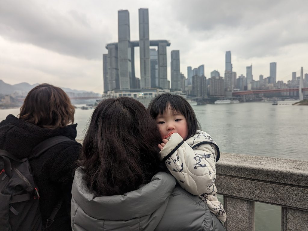 Visitors overlooking the river in Chongqing with Raffles City Chongqing and the modern skyline in the background