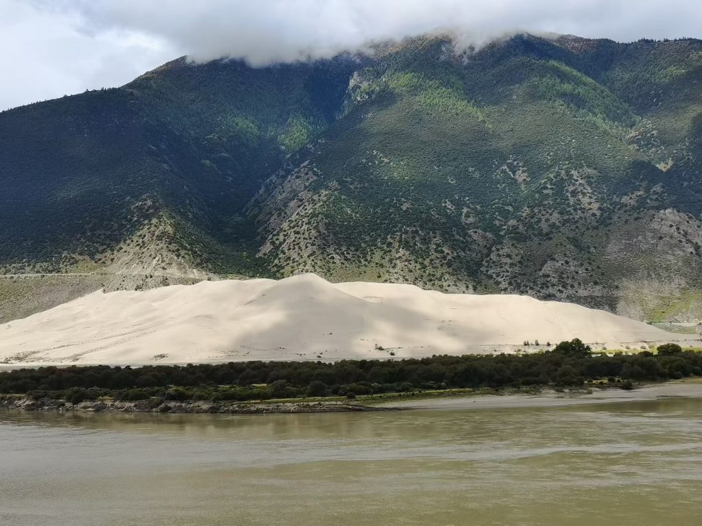 Golden sand dunes and turquoise Yarlung Tsangpo River under blue sky in Tibet’s Grand Canyon near Nyingchi.