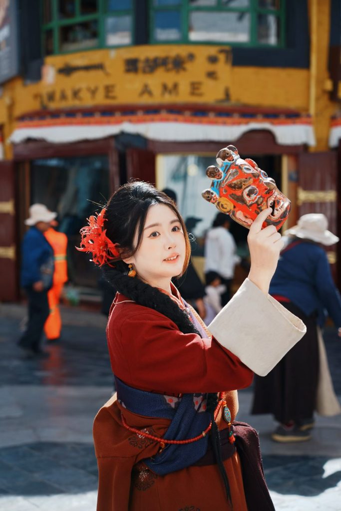 Local woman in Tibetan attire holding a colorful mask at Barkhor Street