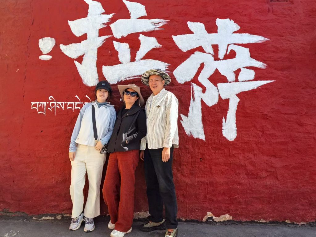 Tourists posing in front of the red “Lhasa” mural wall near Barkhor Street