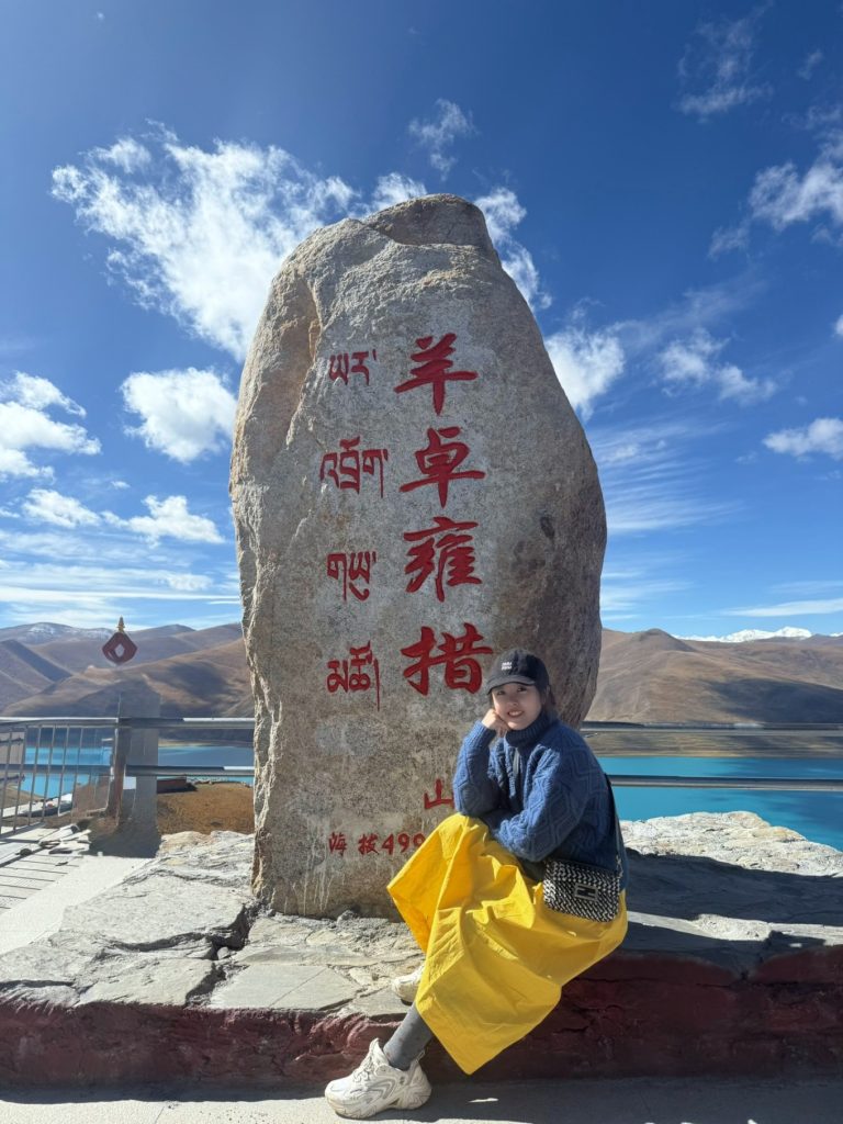 How to Plan a Trip to Tibet? 7 Sitting beside the Yamdrok Lake stone marker under clear blue skies in Tibet