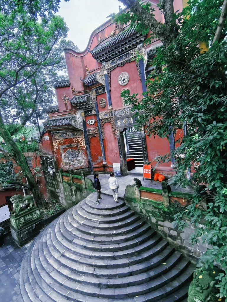 The grand round staircase leading up to the red-walled Laojun Cave temple in Chongqing