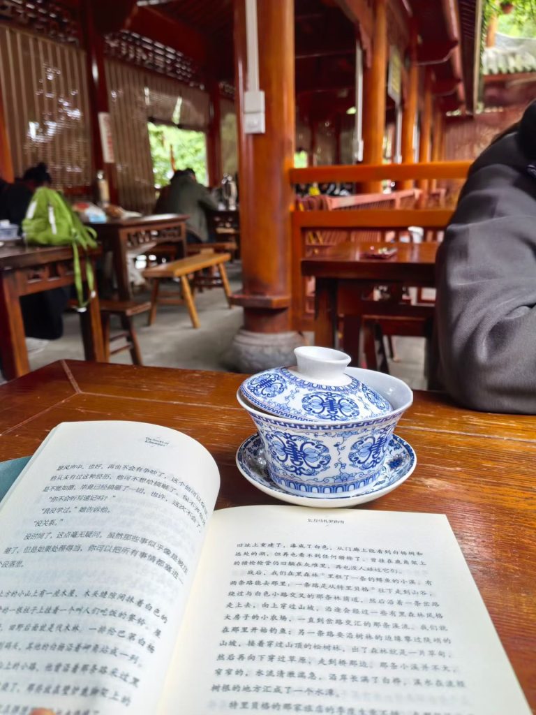 Traditional Chongqing tea house with wooden furniture, open book, and a blue-white gaiwan