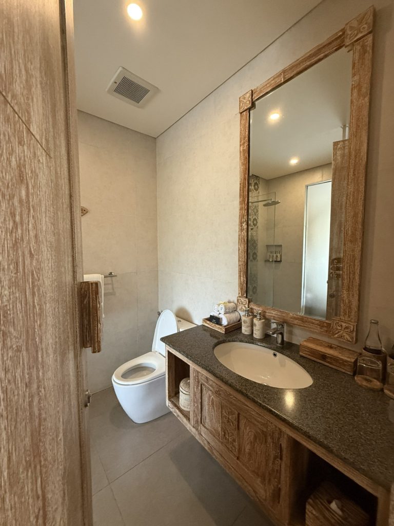 The Sun of Granary Resort and Villas Review: Family Stay Amid Ubud’s Rice Fields 9 Rustic Balinese bathroom with wooden vanity and mirror