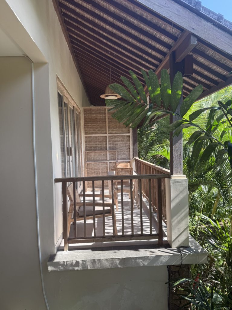 The Sun of Granary Resort and Villas Review: Family Stay Amid Ubud’s Rice Fields 8 Wooden chairs and table on balcony surrounded by palm trees