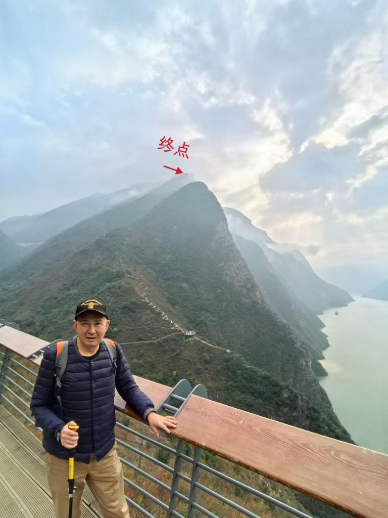 Hiking the Three Gorges Dragon Ridge & Goddess Peak Sky Road 7 Man standing on a viewing platform on the Goddess Peak Sky Road, with an arrow marking the summit “终点” on the opposite ridge.