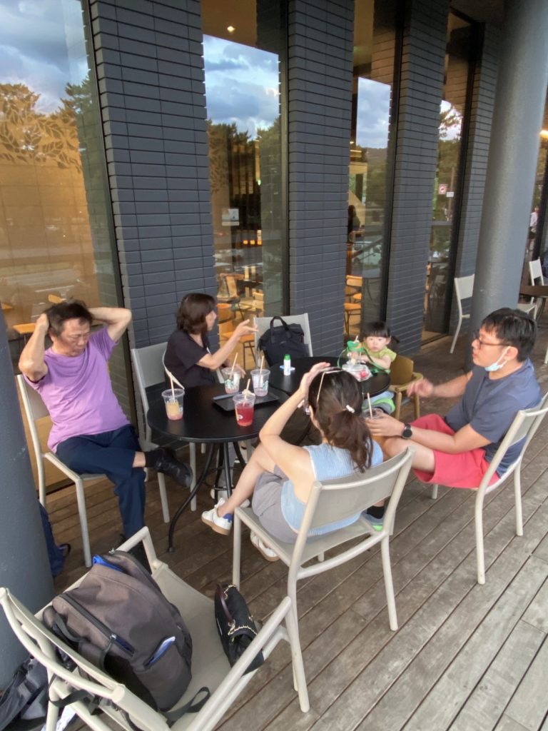 Visiting Nara Park Japan: A Relaxing Family Day with the Friendly Deer 12 Family sitting outdoors at Starbucks Nara Park Bus Terminal, enjoying drinks together.