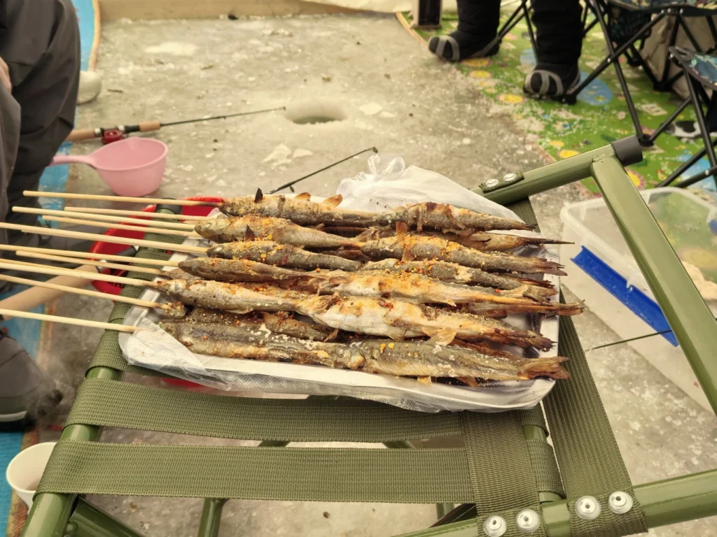 Grilled fish skewers laid on a folding cot inside the ice fishing tent