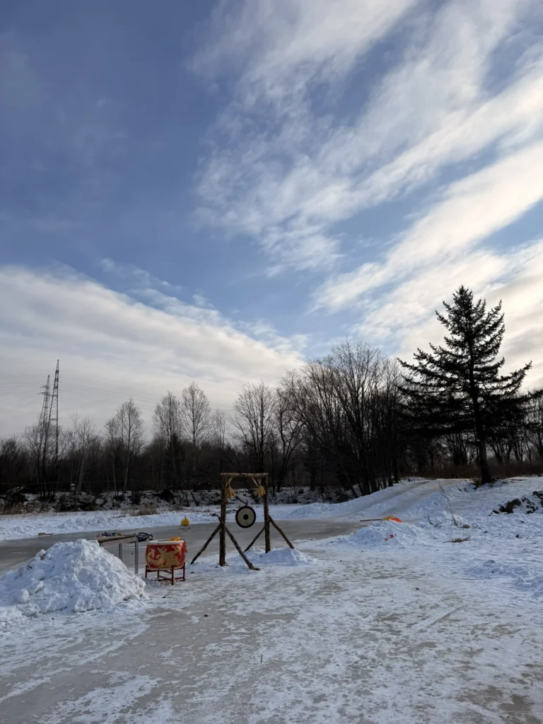 Wide snowy view with a wooden target stand and winter activity props near a frozen path