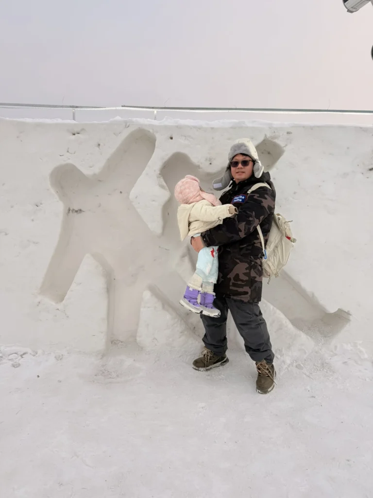 Visit to Harbin Ice and Snow World: What It’s Really Like 17 Adult holding a child beside carved snow wall at Harbin Ice and Snow World