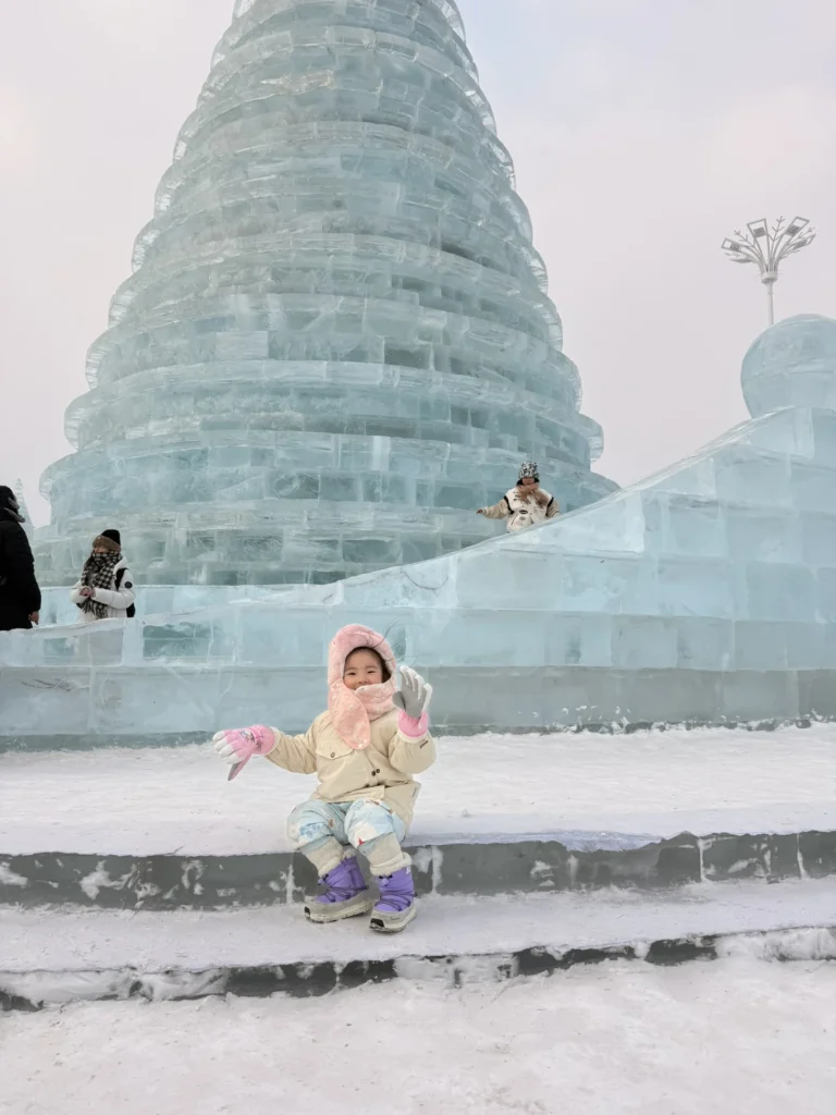 Visit to Harbin Ice and Snow World: What It’s Really Like 6 Child sitting in front of a massive blue ice structure at Harbin Ice and Snow World