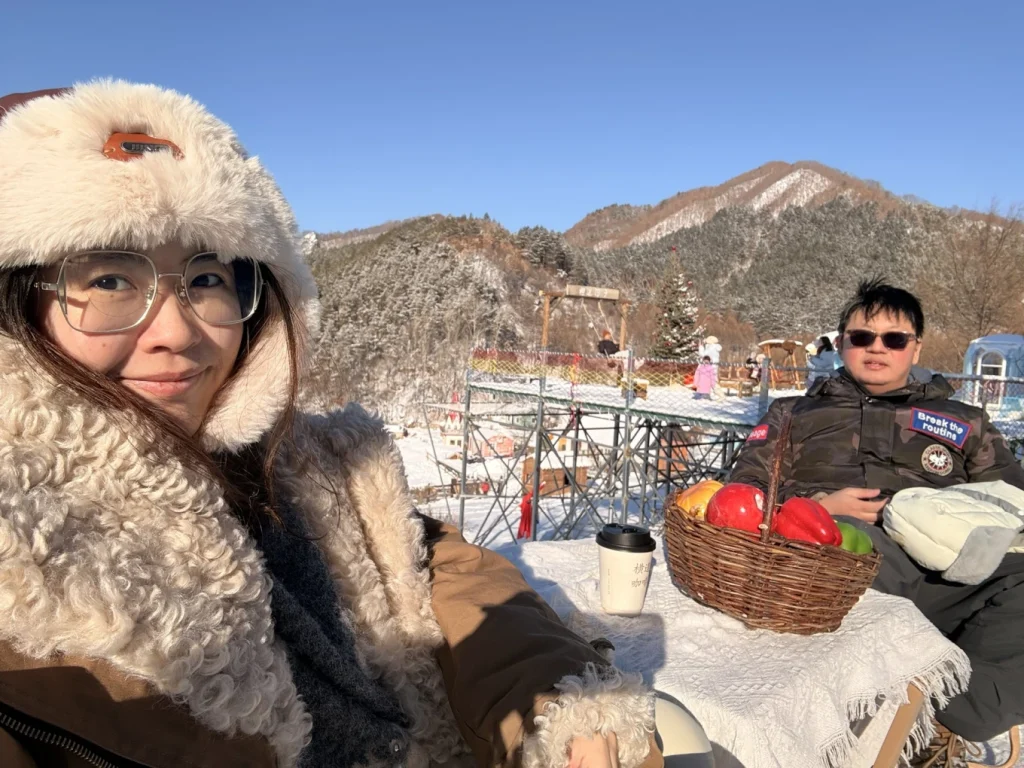 Outdoor café seating on a snowy hillside in Hengdaohezi, overlooking the historic railway town and winter landscape.