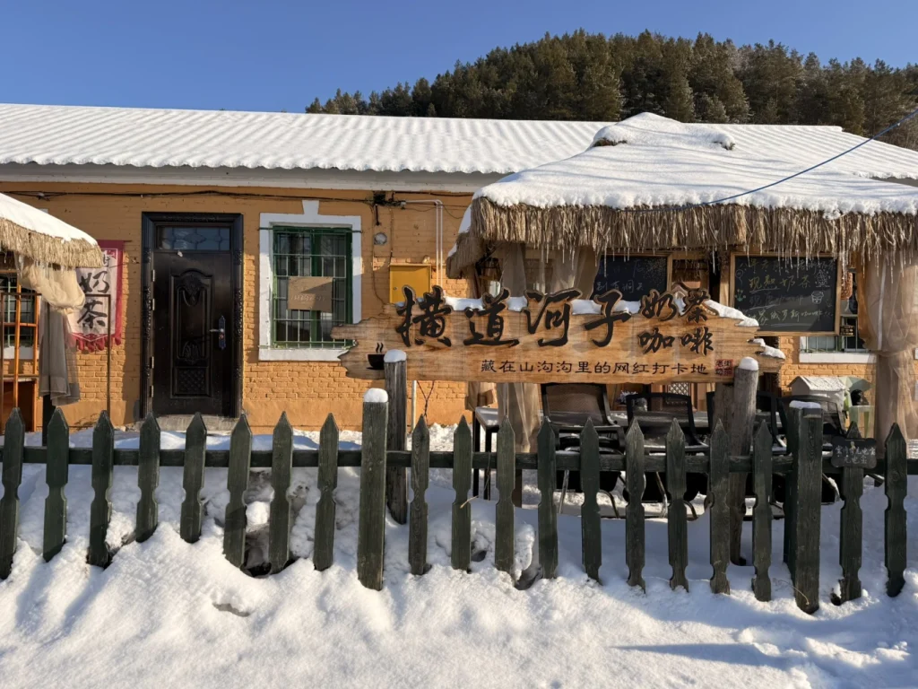 Hengdaohezi 1-Day Trip: Snowy Railway Town Near Harbin Travel Guide 10 Rustic café in Hengdaohezi during winter, with snow-covered roof, wooden signboard, and traditional railway town architecture.