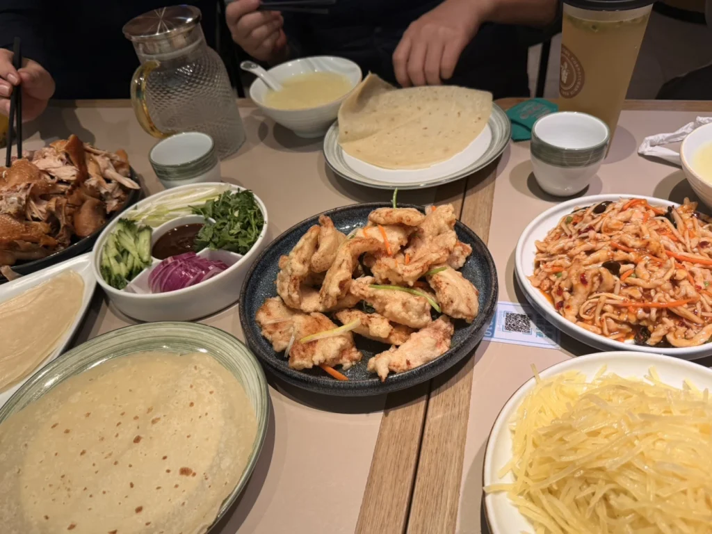 Harbin spring pancake meal with sliced meat, pancakes, shredded vegetables, and dipping sauce at a local restaurant