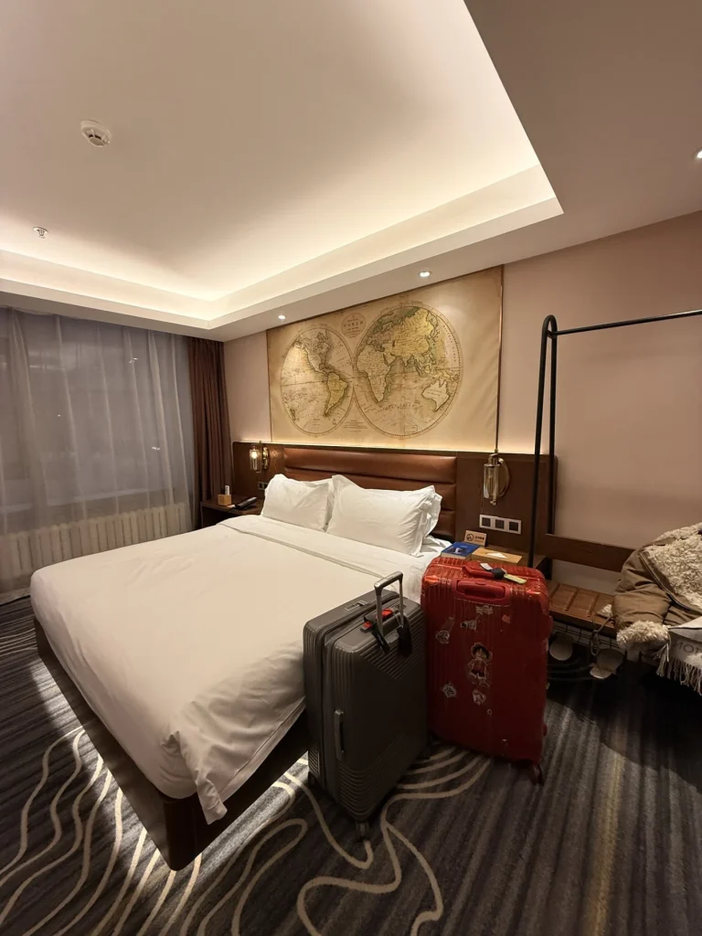 Hotel room in Harbin with double bed, warm lighting, and suitcases placed beside the bed