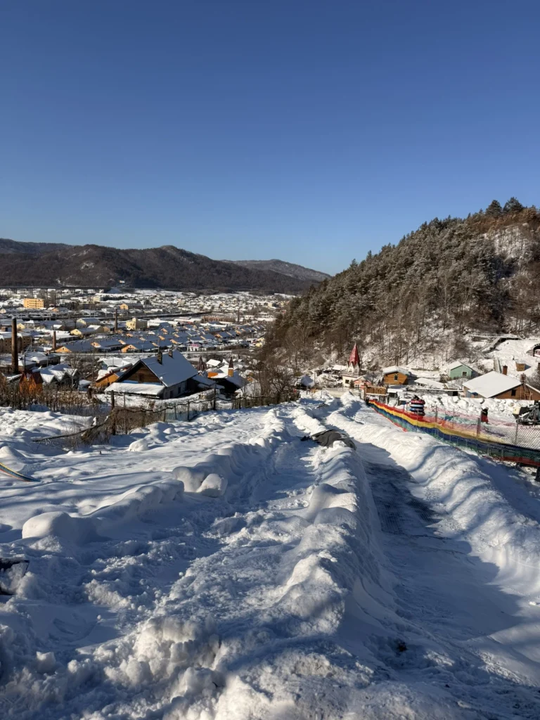 Snow-covered hillside slide in Hengdaohezi overlooking the town and surrounding mountains in winter