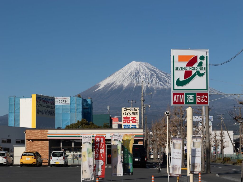 Mount Fuji rising behind a 7-Eleven convenience store on a clear day in Japan