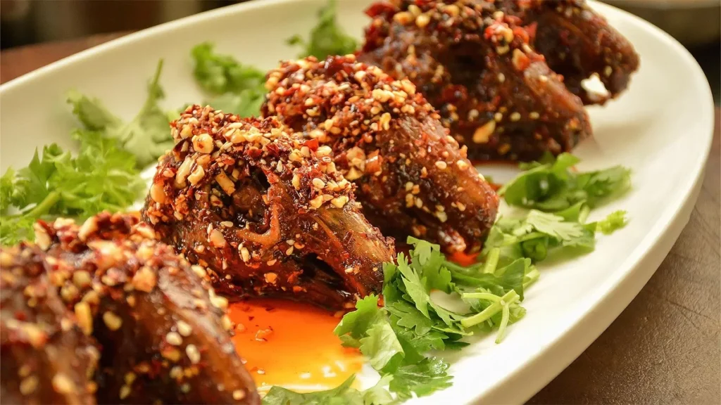 Chongqing spicy rabbit head coated in chili oil, garlic, and sesame seeds on a white plate