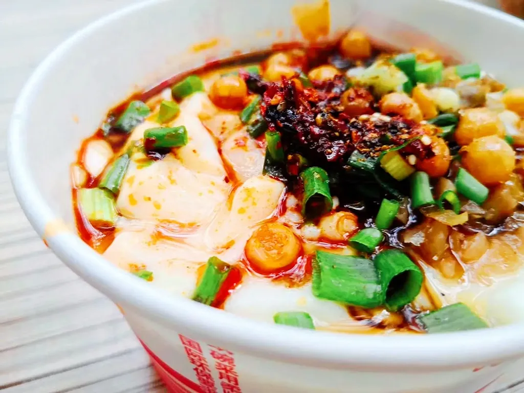 Chongqing savory douhua tofu pudding with chili oil, scallions, peanuts, and preserved vegetables