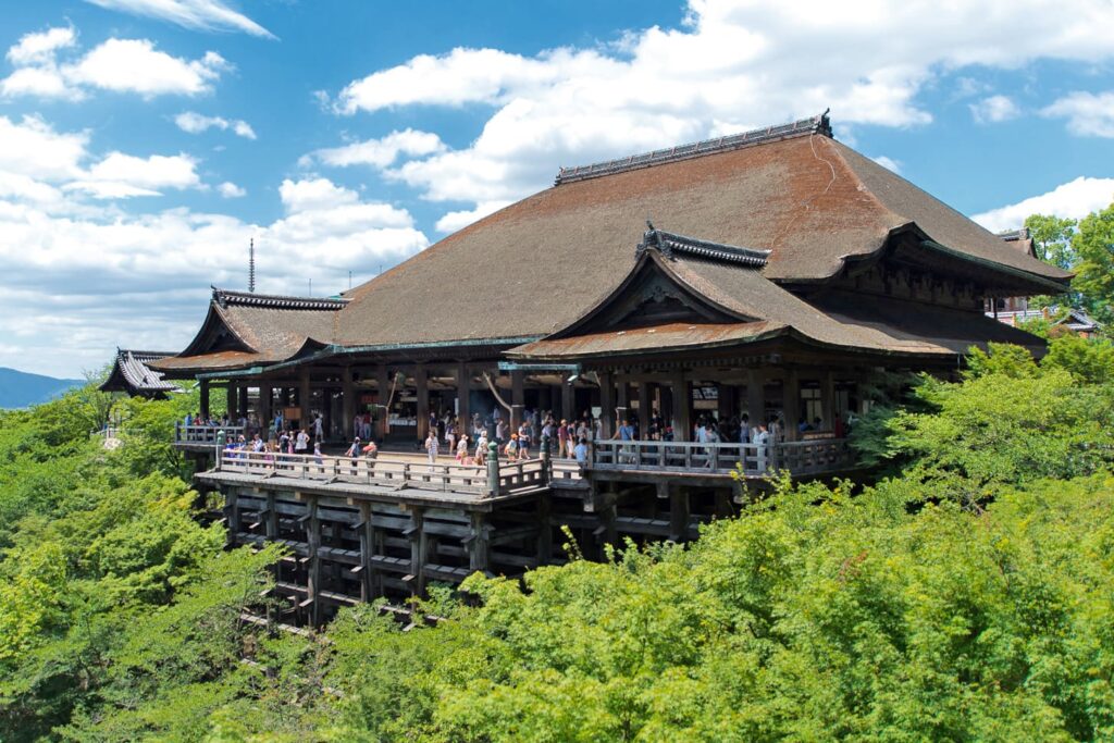 Best Japanese Temples to Visit: Top 6 Must-See Temples in Japan 6 Kiyomizu-dera Temple in Kyoto with its large wooden stage overlooking lush green hills under a bright blue sky