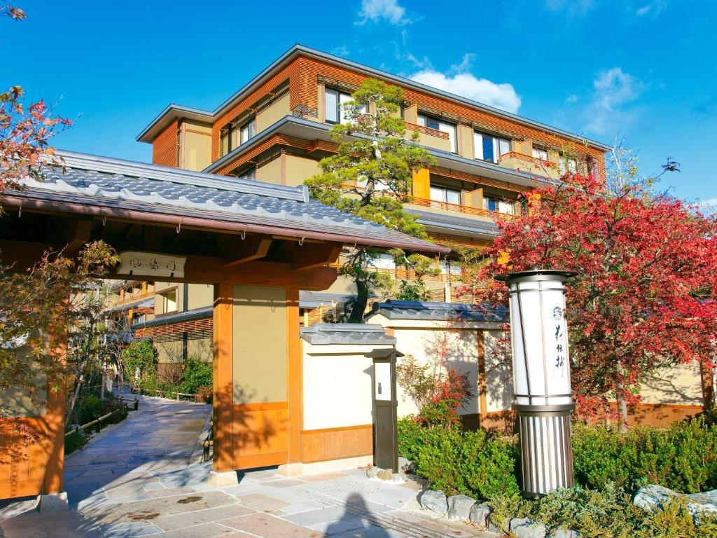Kyoto Arashiyama Onsen Kadensho exterior with traditional Japanese gate, autumn foliage, and modern ryokan building in Arashiyama Kyoto