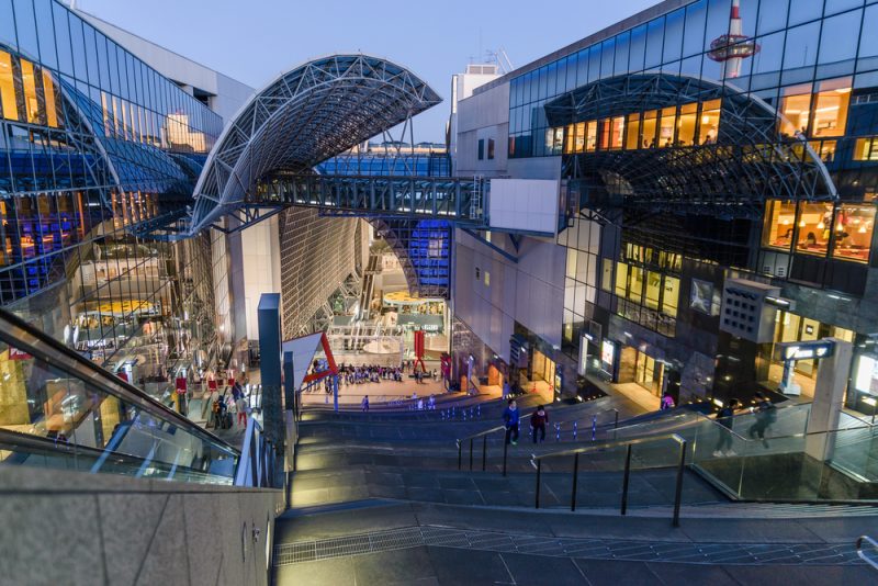 Kyoto Station exterior at dusk with modern glass architecture, escalators, and illuminated shopping complex in Kyoto, Japan