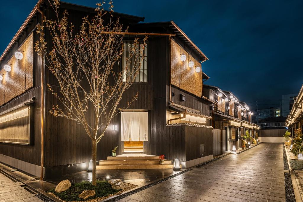 Nazuna Kyoto Tsubaki Street ryokan exterior at night with traditional wooden machiya townhouse architecture and warm lantern lighting in Kyoto