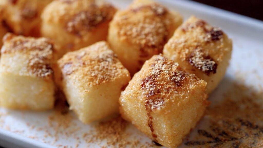 Chongqing brown sugar rice cake cubes dusted with roasted soybean powder on a white plate
