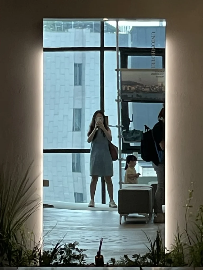 Guest taking mirror photo inside Union Hotel Seoul lobby area near elevator corridor
