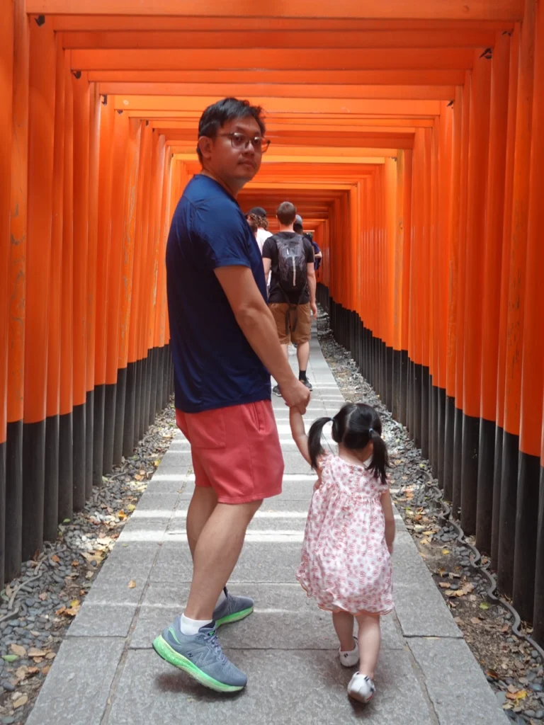 father and child walking through torii gates Fushimi Inari Taisha Kyoto Japan
