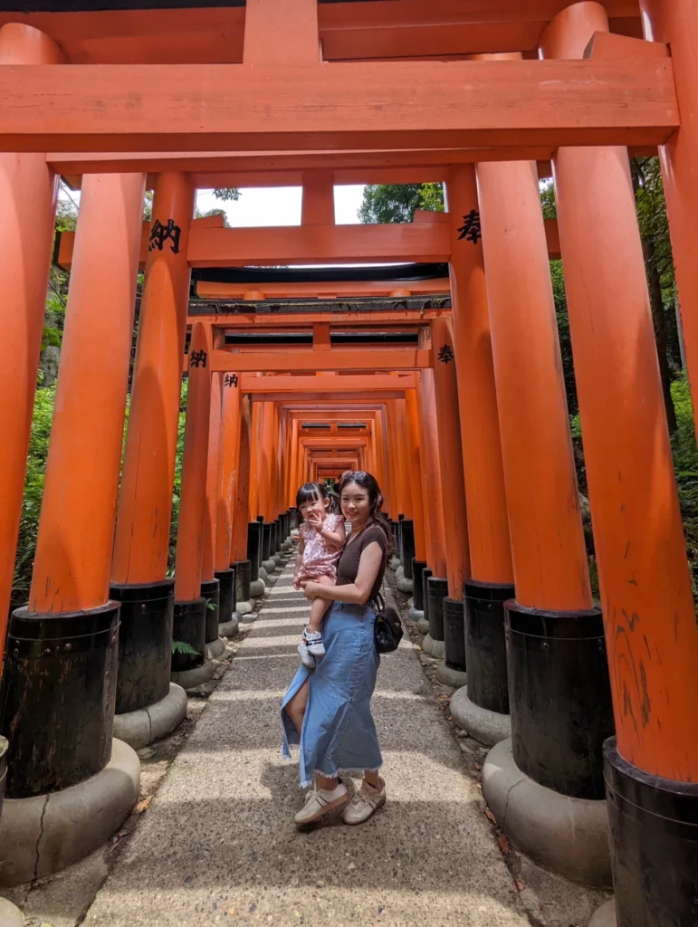 mother holding child under torii gates Fushimi Inari Taisha Kyoto scenic path