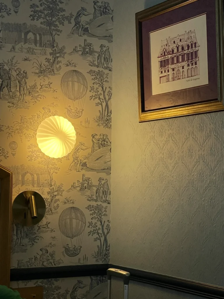Hôtel De Neuve by HappyCulture Review: Boutique Charm in Le Marais 8 Close-up of textured wallpaper and brass light switch in Hôtel De Neuve by HappyCulture Paris room