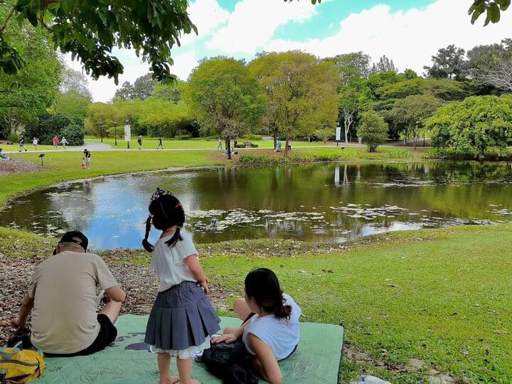 5 Best Asian Countries to Visit With Toddlers (Ranked) 6 Family picnic by the lake at Singapore Botanic Gardens with child playing on grass near water