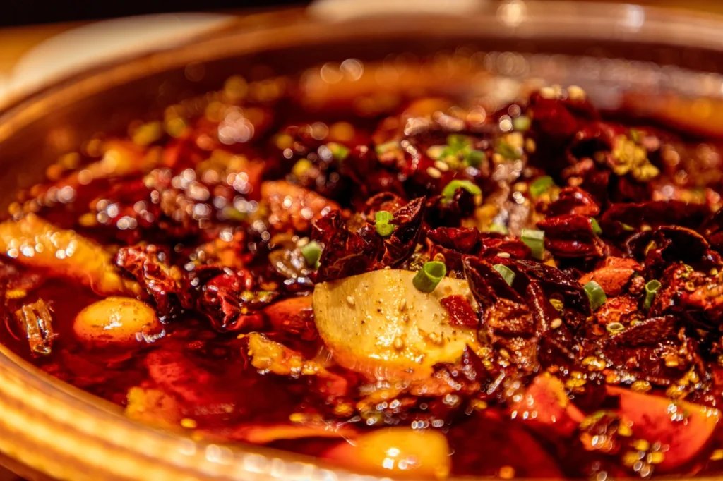 Authentic Chongqing spicy hot pot with chili oil, peppercorns, and simmering broth filled with ingredients