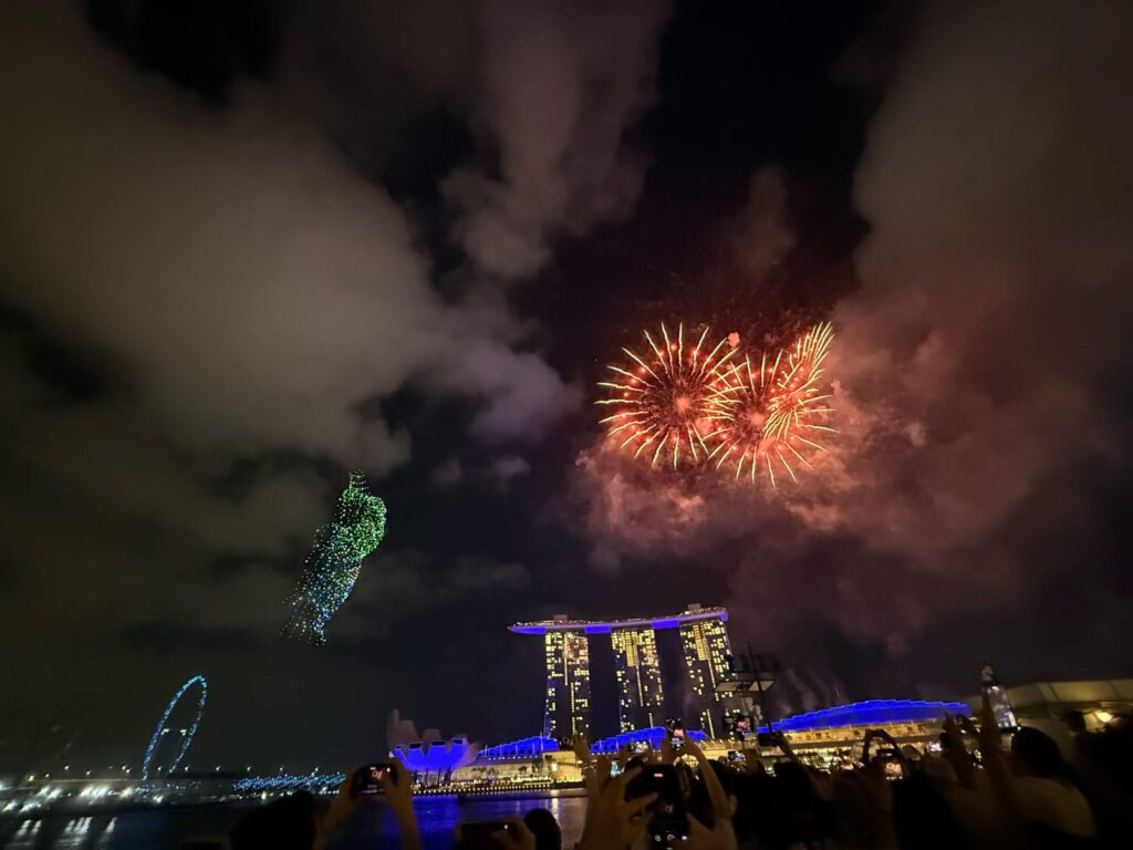 Disney Fireworks and Drone Show at Marina Bay Singapore (Family Experience Guide) 11 Green drone figure beside fireworks above Marina Bay Sands during Disney Cruise Line drone show