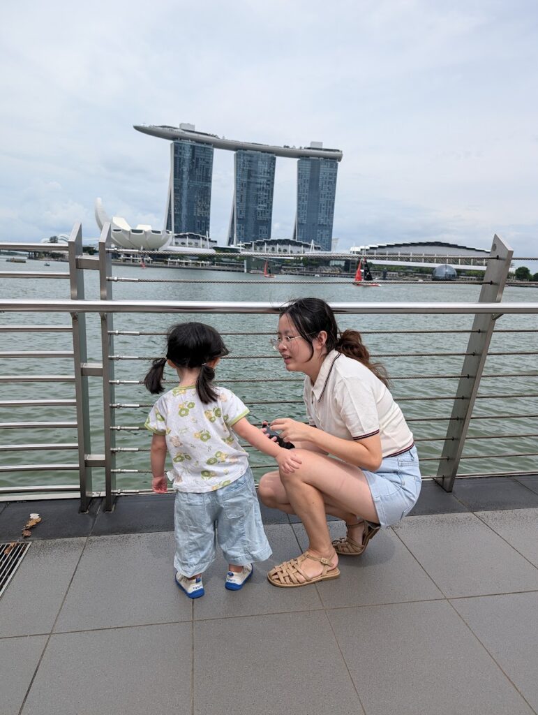 Merlion Park Singapore: The Complete Visitor's Guide 8 Child and mum looking out at Marina Bay Sands from railing, back view