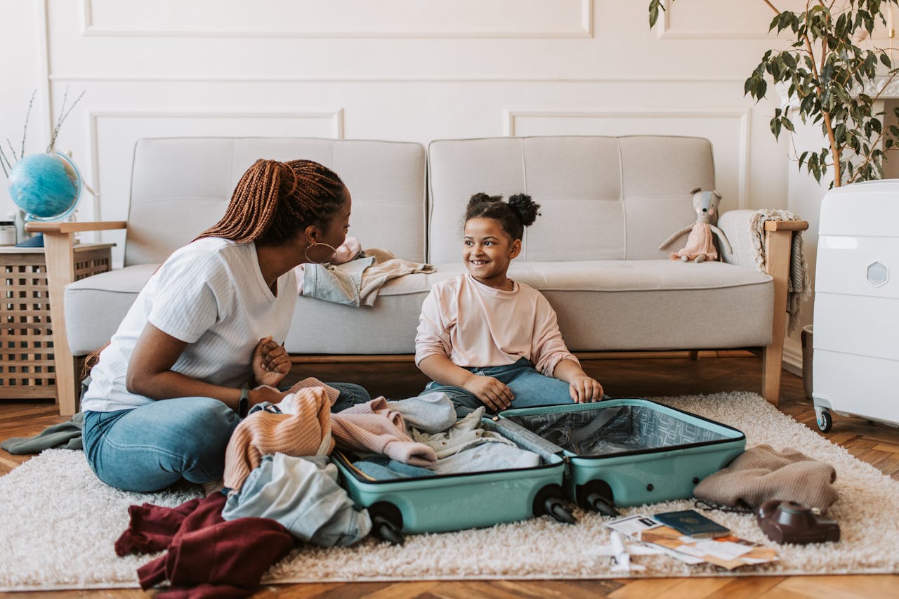 Mother and toddler packing a suitcase together on the living room floor before a family trip
