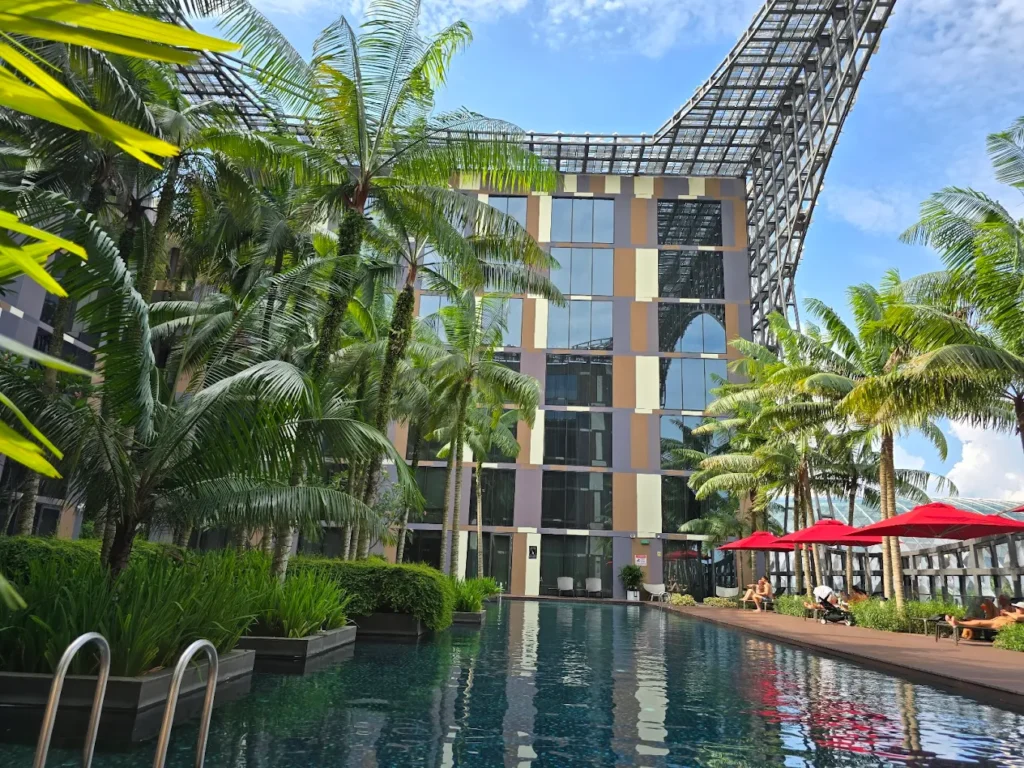 4 Best Hotels Near Changi Airport (Perfect for Layovers & Early Flights) 6 Crowne Plaza Changi Airport outdoor pool surrounded by palm trees and modern hotel building in Singapore