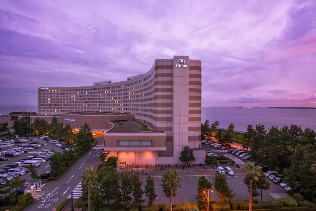 Hilton Tokyo Bay hotel exterior at sunset with curved building facing the waterfront near Tokyo Disney Resort