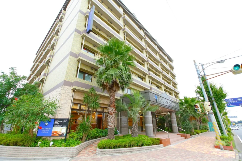 Exterior of Hotel Mystays Maihama with modern building, palm trees, and entrance near Tokyo Disney Resort