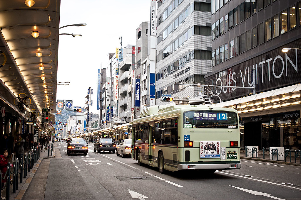 Busy Kawaramachi street in Kyoto with city traffic, shops, and public bus in downtown district