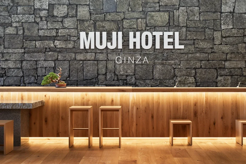 6 Best Boutique Hotels in Ginza Tokyo: Stylish & Unique Stays Guide 8 MUJI Hotel Ginza reception area with minimalist wooden design, stone wall, and clean Japanese interior style
